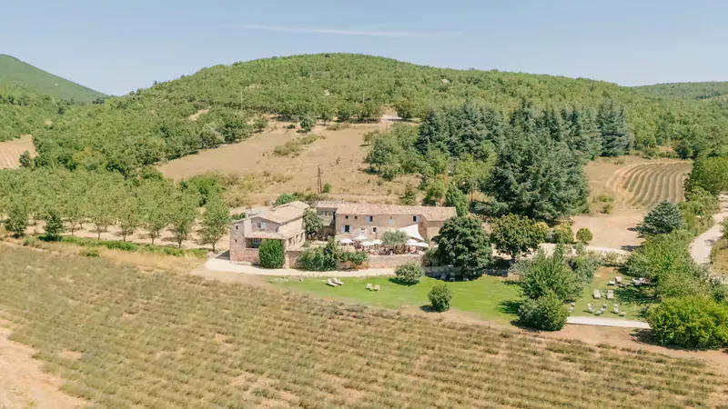 Vue aérienne du Hameau de l’Esperelle au milieu des collines boisées et des champs de lavande